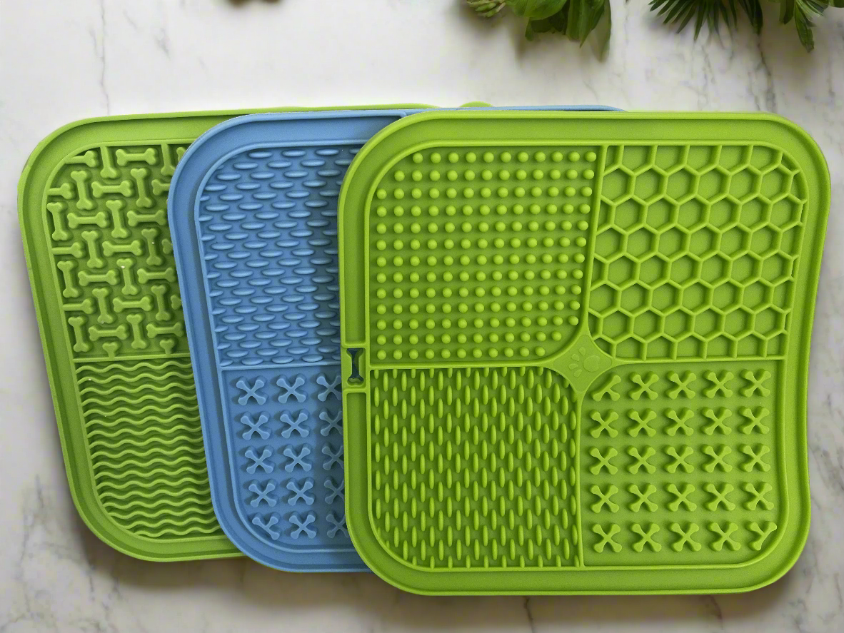 Three green and blue silicone mats with textured surfaces on a white surface.