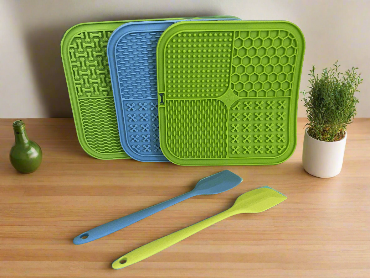 Three silicone mats with different patterns and two spatulas on a kitchen counter.